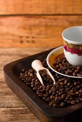 Empty cup and coffee beans in wooden tray