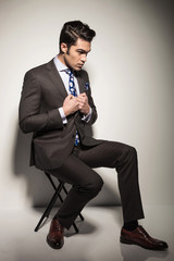 business man sitting on a stool while fixing his jacket