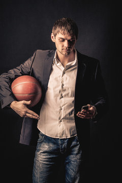 Young man holding basketball ball and celling by the phone