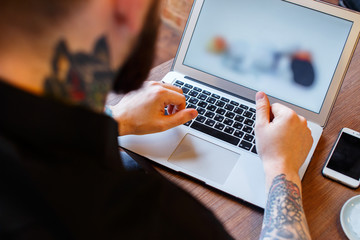 Tattoe man with beard and laptop.