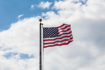 American Flag Blowing in Wind Under Clouds