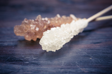 Candy brown and white sugar on a sticks on wooden background