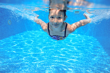 Kid swims in pool underwater, girl swimming having fun