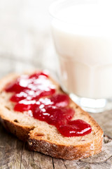 Bread with strawberry spread and glass of milk