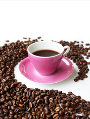 Tazzina di caffè rosa dentro curva di chicchi caffé