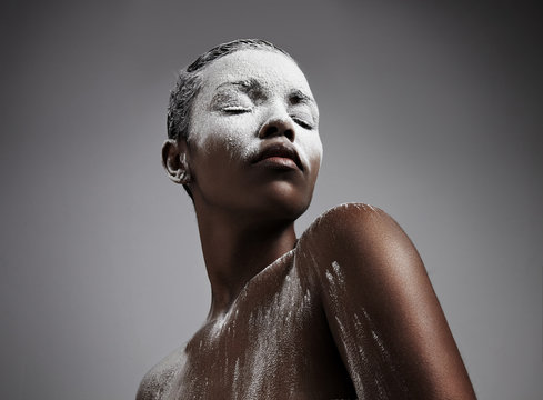 black woman covered by white powder. looking like a mountain