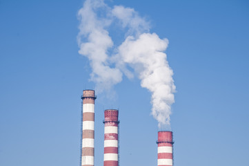 Smoking chimneys of thermal power plant on clear blue sky
