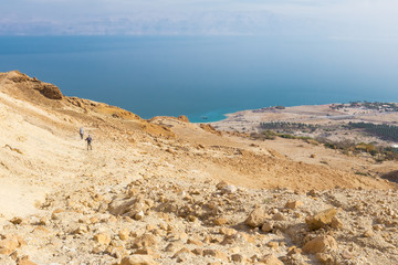 Couple walking desert trail down to Dead sea.