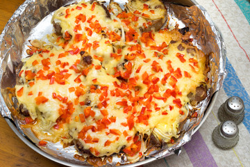 frying meat under the cheese laying on a round metall dish