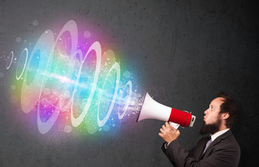 Man yells into a loudspeaker and colorful energy beam comes out