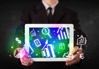 Naklejka premium Young person holding tablet with graph and chart symbols