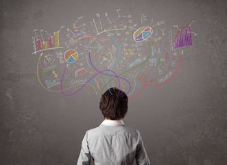 Young business man looking at sketches of graphs and symbols