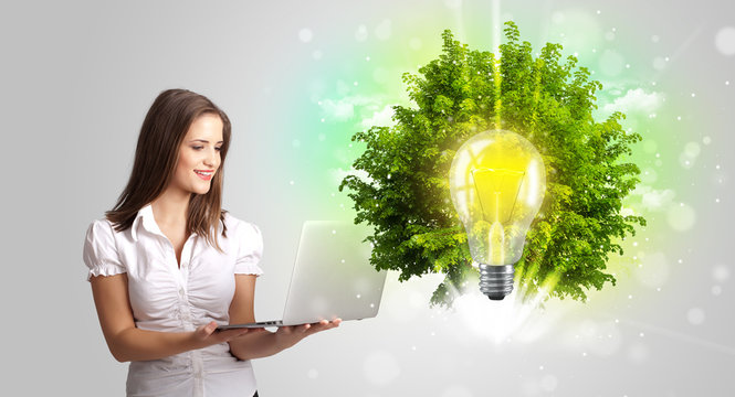 Young girl presenting idea light bulb with green tree