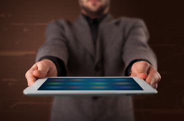 Businessman holding a white modern tablet with blurry apps