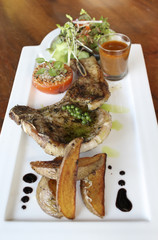 A grilled rib-eye steak with salad on white plate.