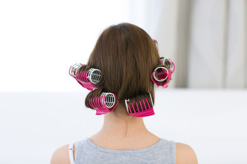 Naklejka premium Back view portrait of a woman with curlers on her head
