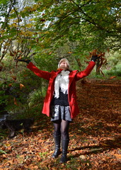 Girl throwing leaves in autumnal woods