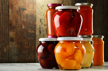 Jars with pickled vegetables, fruity compotes and jams isolated