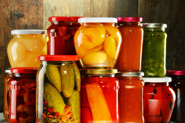 Jars with pickled vegetables, fruity compotes and jams isolated