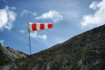 Red and white windsock blows against a cloudy sky