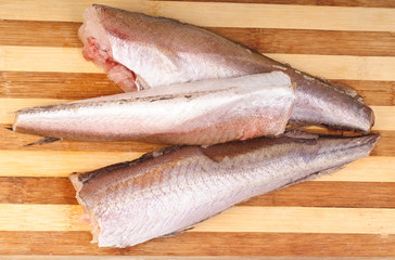 frozen fish hake on cutting board background