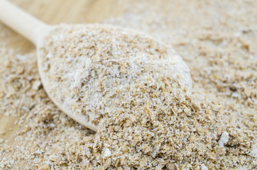 Wholemeal flour macro on wooden spoon. Healthy vegetarian food.