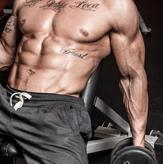 Sexy sportsman with dumbbells in gym