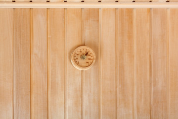 Round thermometer on the wall of traditional wooden sauna