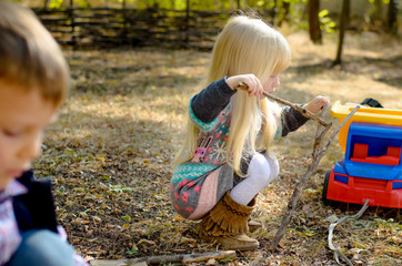 Little Blond Girl Playing Sticks on the Ground