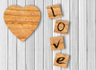 Wood heart on white wooden background. Love cast out of wood kub