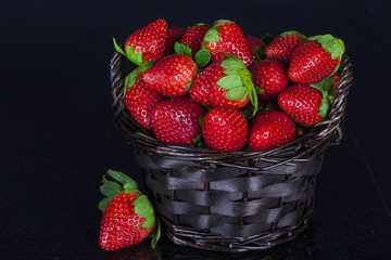 Strawberries in a basket on a black background.