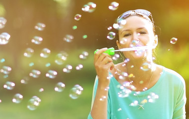 Gorgeous young brunette girl blowing soap bubbles