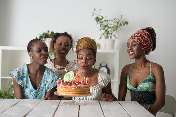 Girl looking at birthday cake surrounded by friends