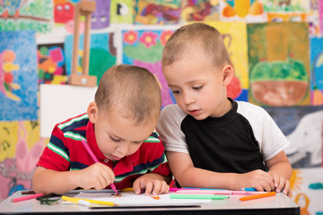 Two brothers enjoy drawing with felt tip pens.
