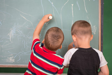 Two little boys drawing with chalk on a chalkboard