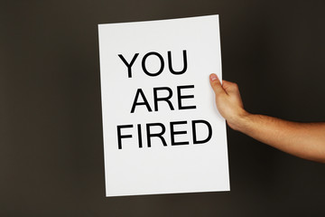 Sheet of paper with text You Are Fired in male hand