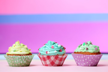 Delicious birthday cupcakes on table on bright background