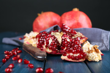 Juicy ripe pomegranates on wooden table, on dark background