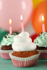 Delicious birthday cupcakes on table on bright background