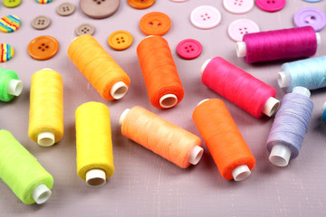Colorful buttons and sewing threads on wooden background
