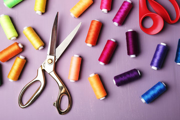 Multicolor sewing threads with scissors on wooden background