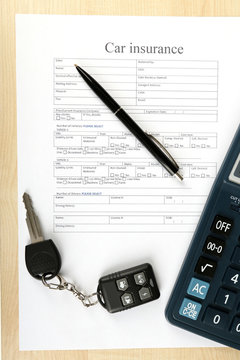 Car keys on insurance documents, close up