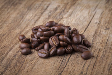 roasted coffee beans in wooden spoon placed on coffee beans as b