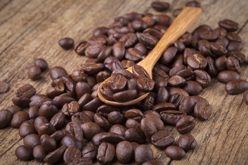 roasted coffee beans in wooden spoon placed on coffee beans as b