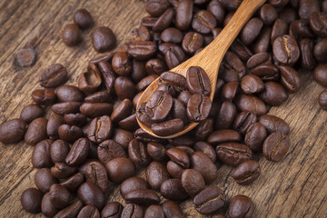 roasted coffee beans in wooden spoon placed on coffee beans as b