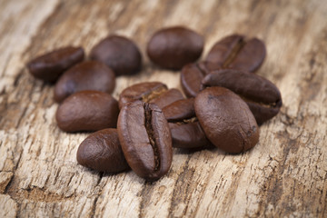 roasted coffee beans in wooden spoon placed on coffee beans as b