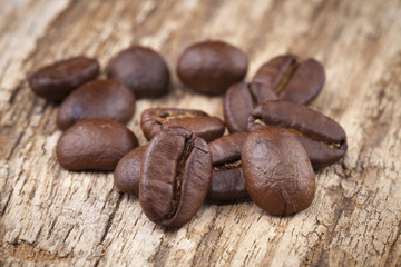 roasted coffee beans in wooden spoon placed on coffee beans as b
