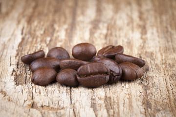 roasted coffee beans in wooden spoon placed on coffee beans as b