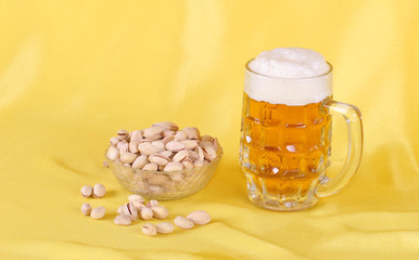 Glass mug with light beer and foam and a plate of snacks