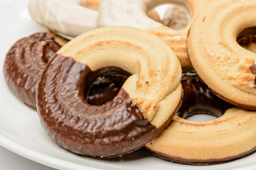 Close up of ring shaped chocolate biscuits in a porcelain plate isolated on white background